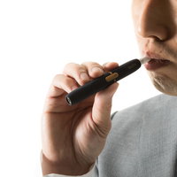 加熱式たばこIQOSを吸う男性の口元のクローズアップの写真