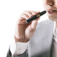 加熱式たばこの味を確かめる白いシャツの男性の写真