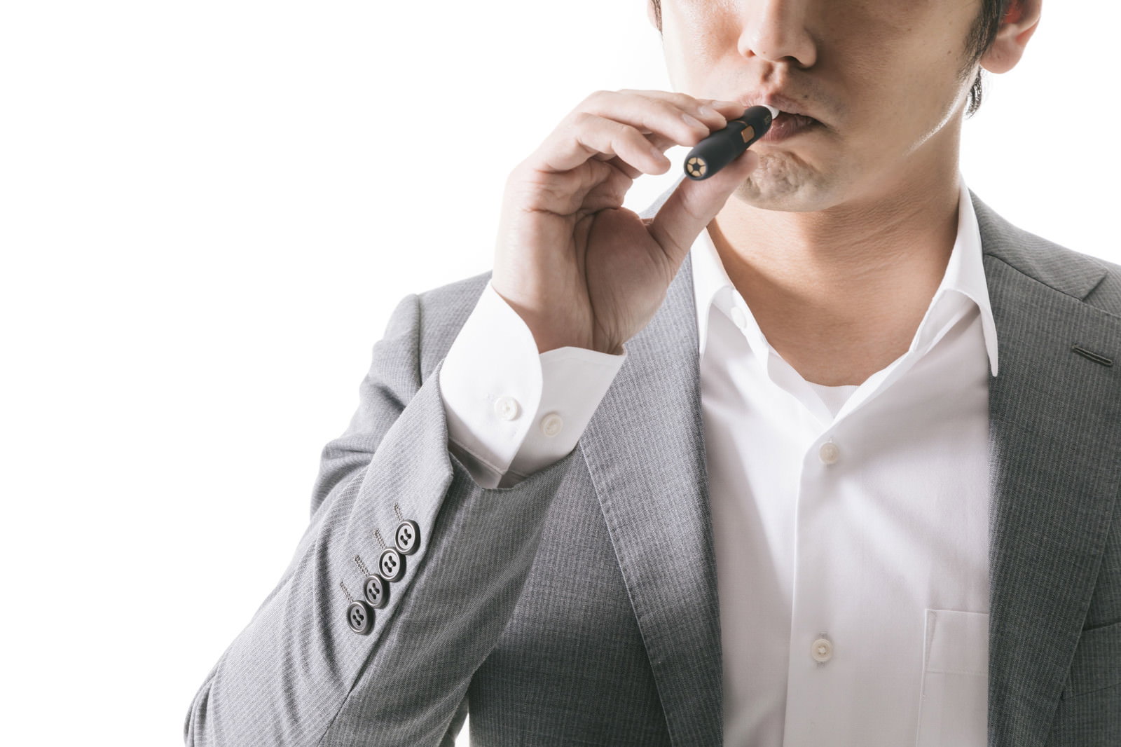 グレーのスーツを着た男性が電子タバコを吸っている［モデル：大川竜弥］