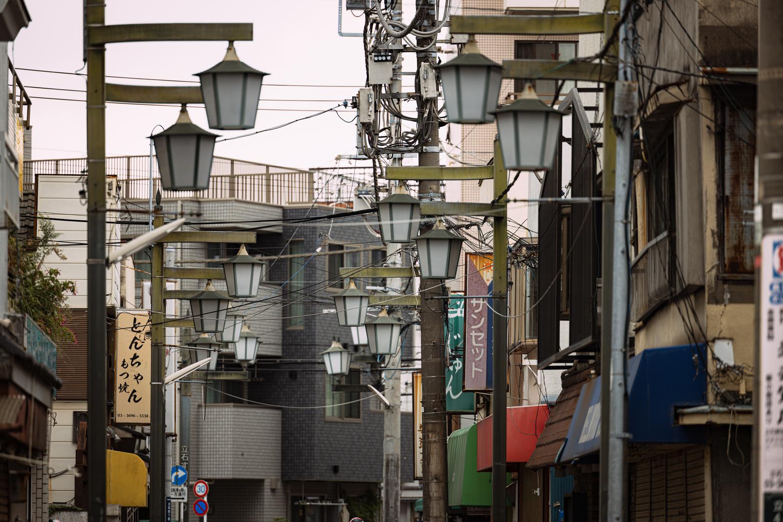 緑色の街灯が並ぶ昭和レトロな商店街の通り