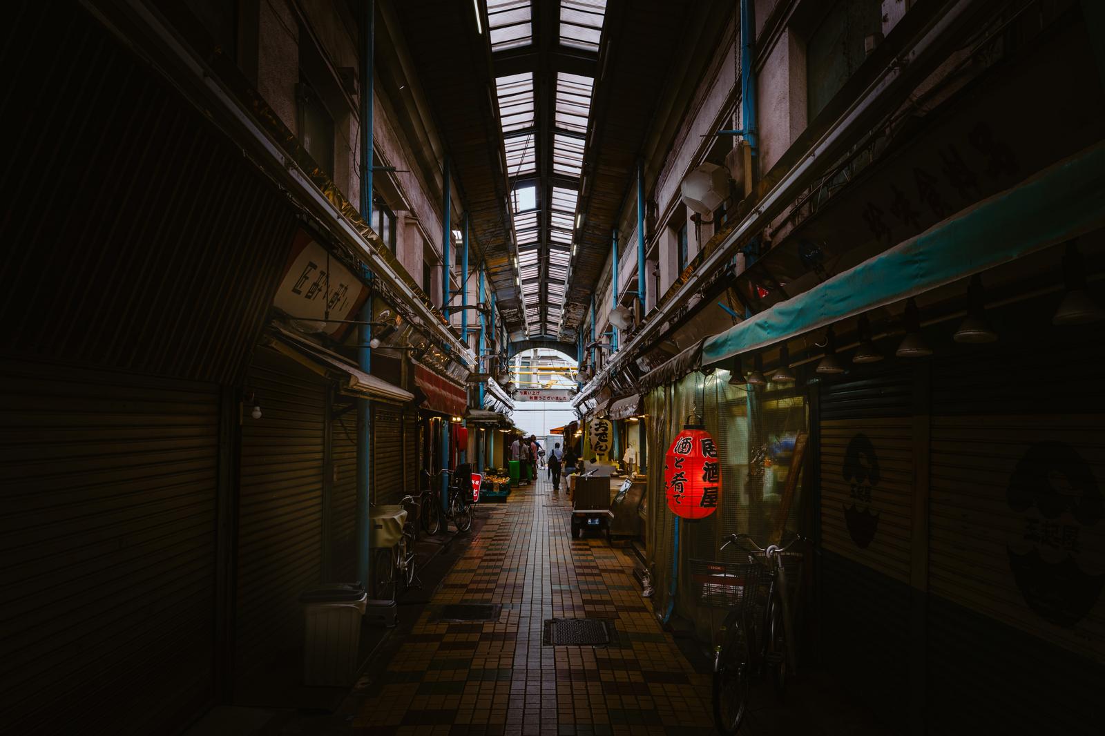 古い商店街のアーケード通りに赤い提灯と店舗が両側に並んでいる風景
