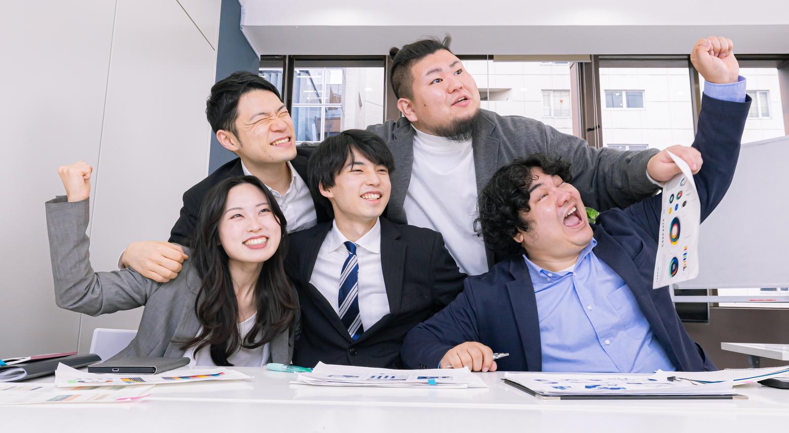 オフィスの会議室で両手を上げてガッツポーズをするビジネスマンとビジネスウーマンのチーム［モデル：たくみ 吉屋ゆり 段田隼人 ノリックス モデルリリース］