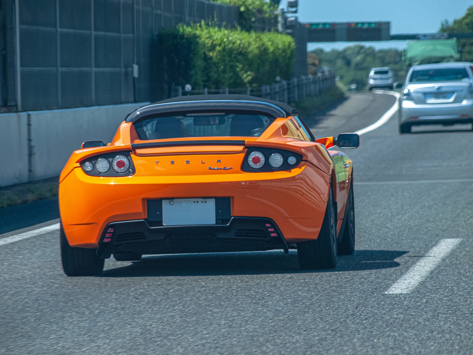 高速道路を走るオレンジ色のテスラスポーツカー