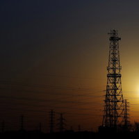 霞む空に夕日と送電線のシルエット、黄昏の電力インフラの写真