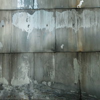 下部が崩れかけるグレーコンクリートの壁テクスチャーの写真