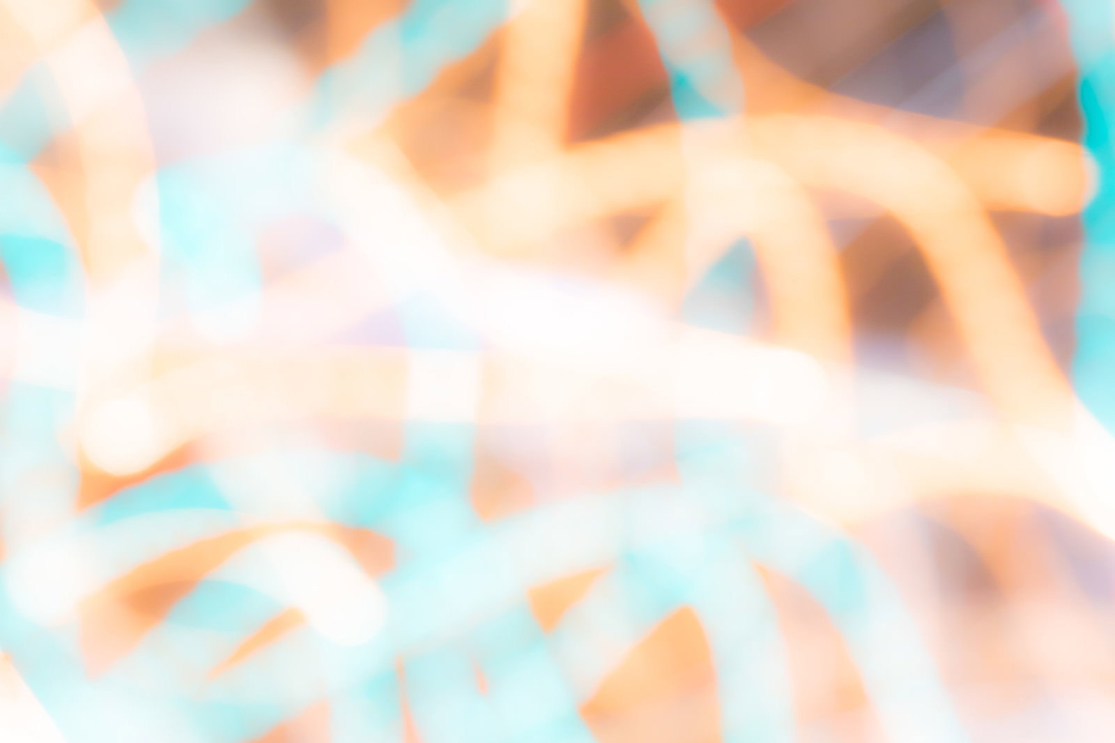 オレンジと水色の光が重なり合う幻想的な光跡とボケの背景