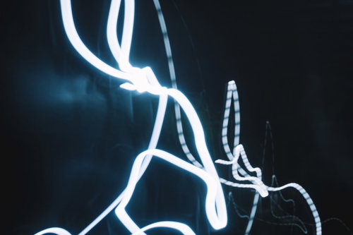 暗い背景に白く流れる光跡、ネオン調の発光と曲線軌跡