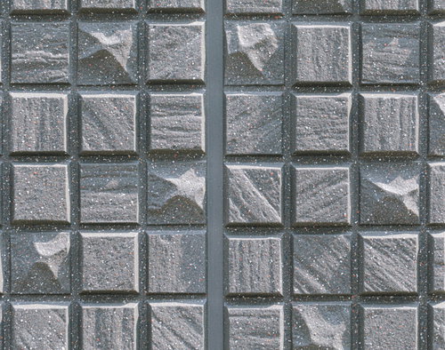 グレーの正方形いびつなタイルの外壁テクスチャー