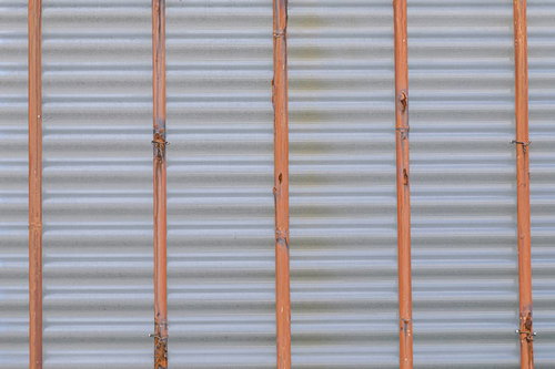 鉄棒で支えるオレンジ色のシャッター裏側の金属テクスチャ
