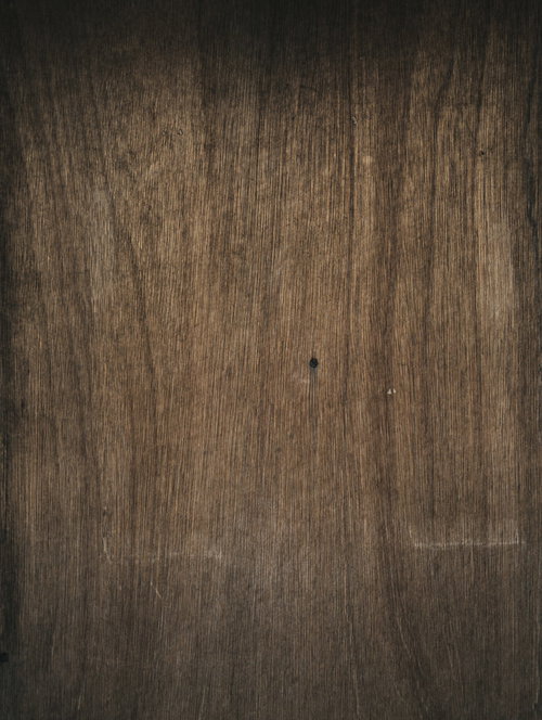 木目が入った板に刺さった黒いネジのテクスチャー