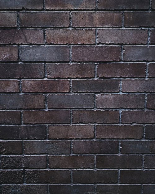 暗がりの中のレンガ外壁のテクスチャー