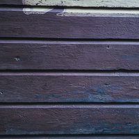 濃い紫色のペイントの跡が残る横張り外壁の板壁テクスチャーの写真