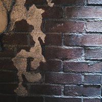 光が差し込む古いレンガ外壁のテクスチャと剥がれたペンキの写真