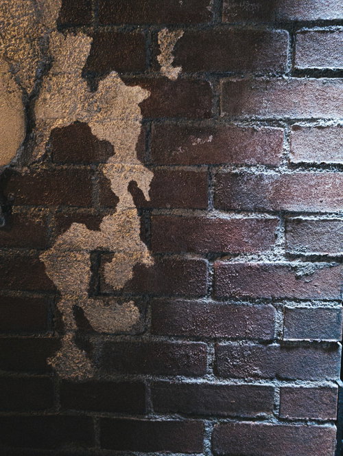 光が差し込む古いレンガ外壁のテクスチャと剥がれたペンキ