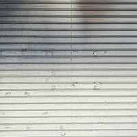 シール跡や汚れが残る金属製ガレージシャッターの写真