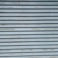 所々擦れたグレーの金属製シャッター（テクスチャ）の写真