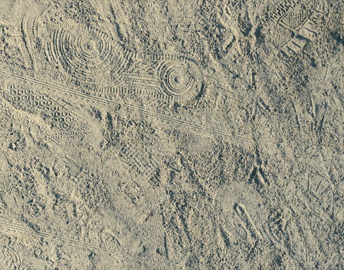 砂地の地面に付いた無数の足跡と靴跡のテクスチャー