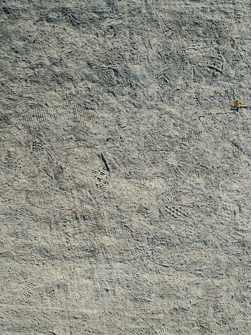 砂地に無数についた自転車のタイヤ痕と靴跡のテクスチャ