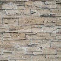 ベージュ・グレー系の石材タイルが並ぶ外壁のテクスチャの写真