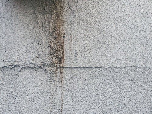 白いモルタル外壁に流れる茶色の雨ダレのシミ