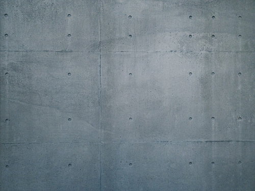 グレーのコンクリート打ちっぱなし壁に規則正しく並ぶセパ穴