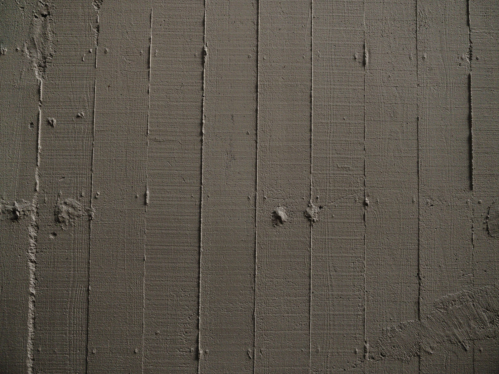 木目の枠板跡が縦に並んで残るグレーのコンクリート壁