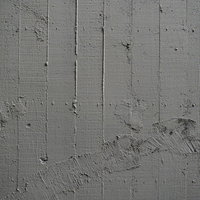 グレーのコンクリート壁に刻まれた枠板跡と補修跡の写真
