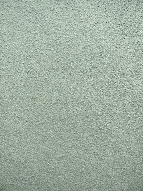 淡いグリーンに塗装されたモルタル壁のテクスチャ