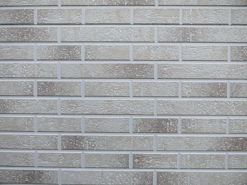 まばらに染みが残るグレーのタイル壁のテクスチャー