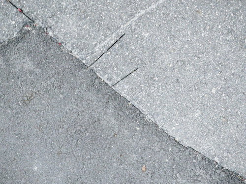 アスファルト舗装の継ぎ目と切れ目が交差するテクスチャ