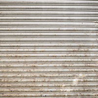 下部から茶色く錆び付く金属製鎧戸のテクスチャーの写真