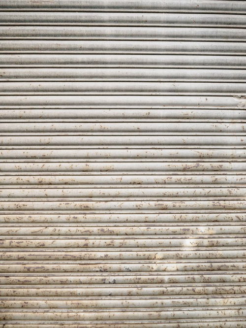 下部から茶色く錆び付く金属製鎧戸のテクスチャー