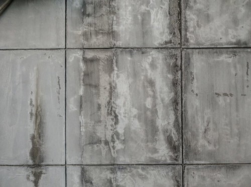 ひび割れと染みが残るグレーのタイル壁テクスチャー