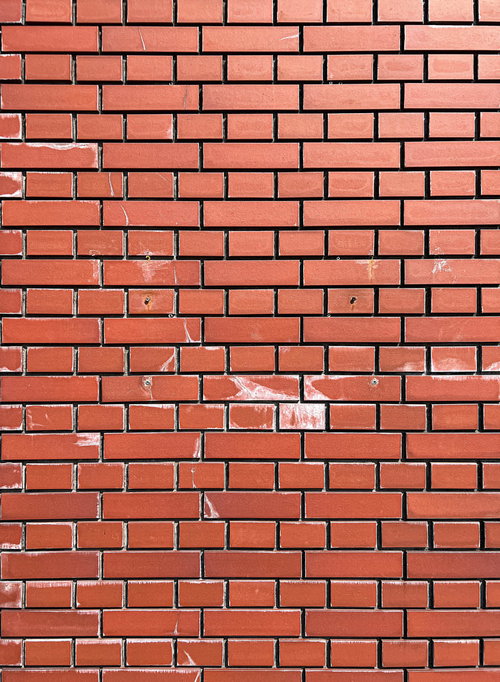 補修跡が残る赤茶色のレンガ壁のテクスチャー
