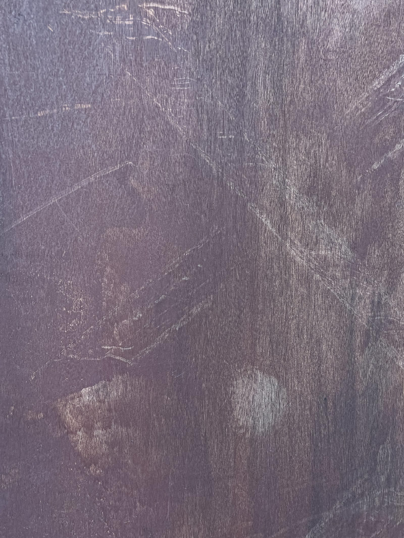 グレーがかった紫色のベニア板に傷や汚れの跡が残るテクスチャ