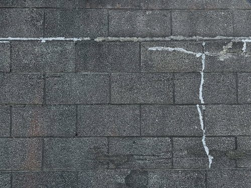 ひび割れを補修したグレーのブロック塀のテクスチャー