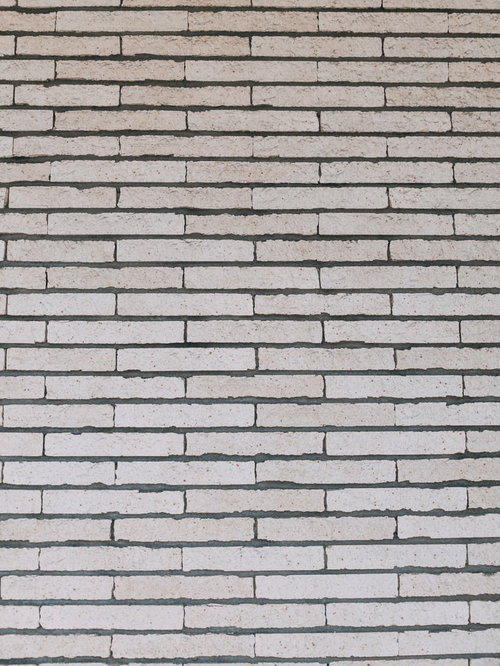 グレー系の石材タイル外壁、規則的に並ぶ長方形タイルの目地テクスチャ