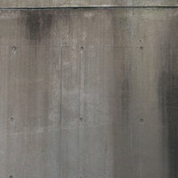 水の垂れた跡が残るグレーのコンクリート打ちっぱなし壁の写真