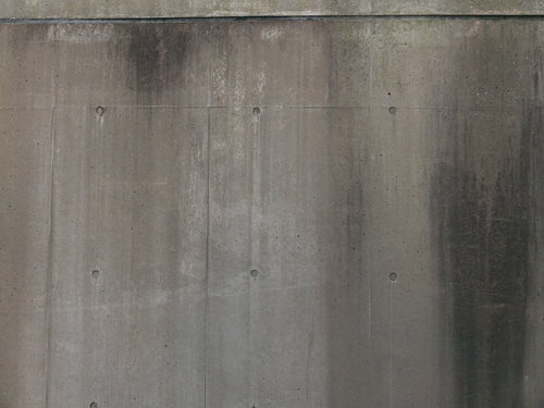 水の垂れた跡が残るグレーのコンクリート打ちっぱなし壁