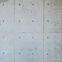 規則的な円形の穴が並ぶコンクリートむき出しの壁の写真