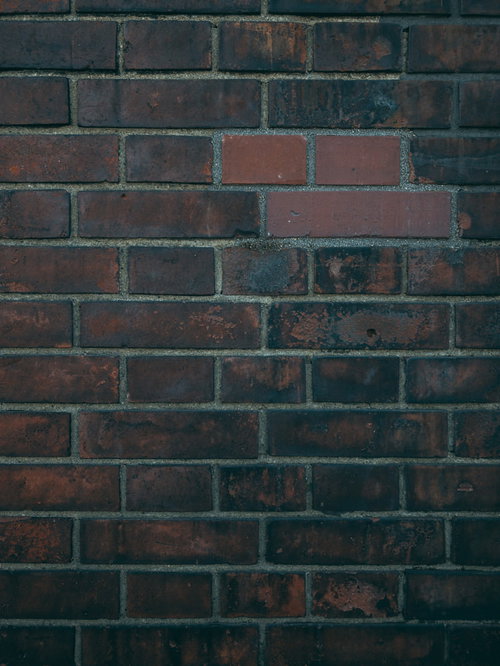黒く汚れた赤茶色のレンガ壁のテクスチャー