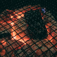 焼き肉を焼く網と赤く燃える備長炭の炭火グリルの写真