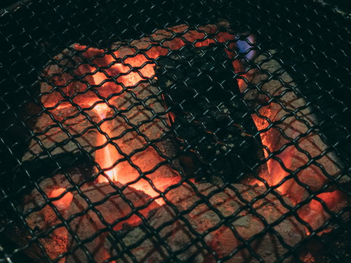 焼き肉を焼く網と赤く燃える備長炭の炭火グリル