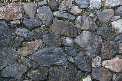 大小の自然石が積み重ねられた石垣のテクスチャ