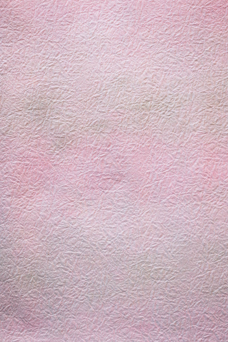 シワが入った淡いピンク色の紙のテクスチャー背景