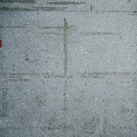 シール跡が残るグレーのコンクリート壁の表面テクスチャーの写真