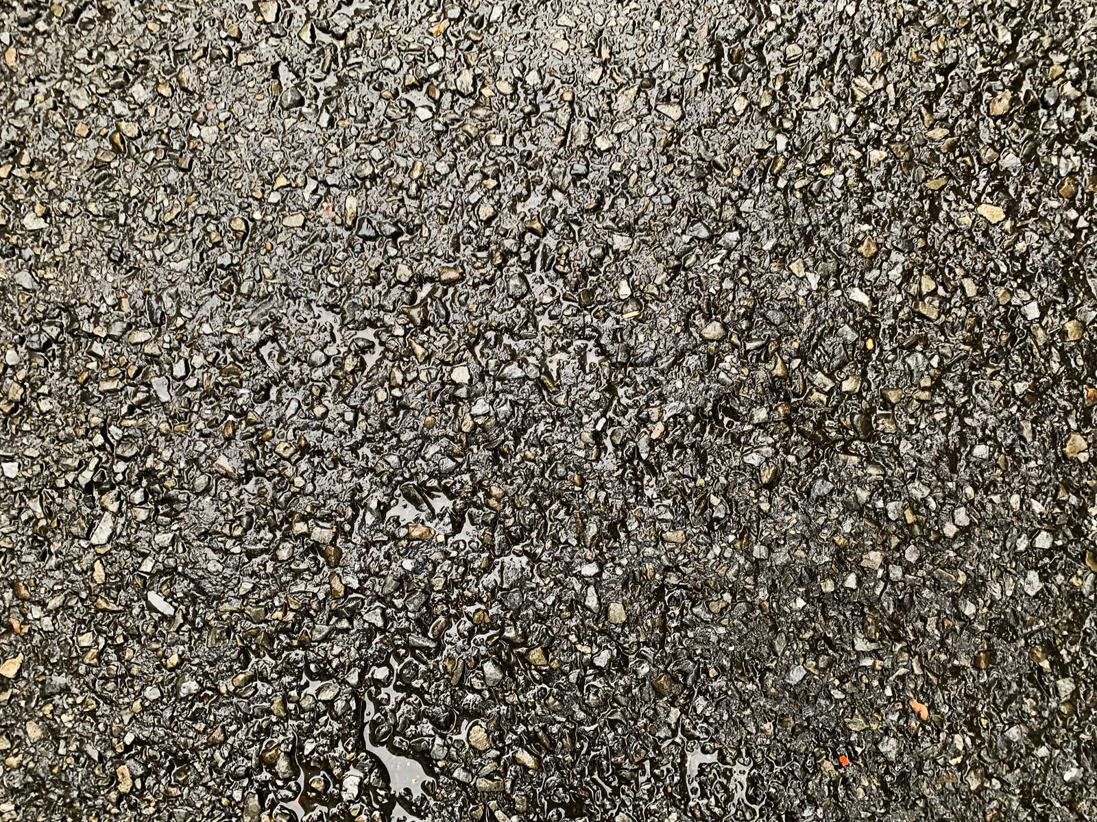 雨に濡れて光るアスファルト舗装の路面テクスチャー