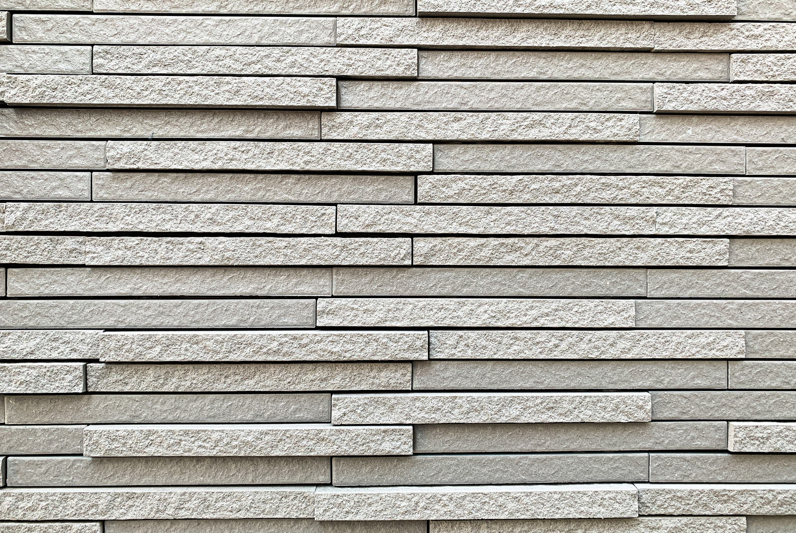 グレーの細長い凸凹した外壁タイルが規則的に並んでいる