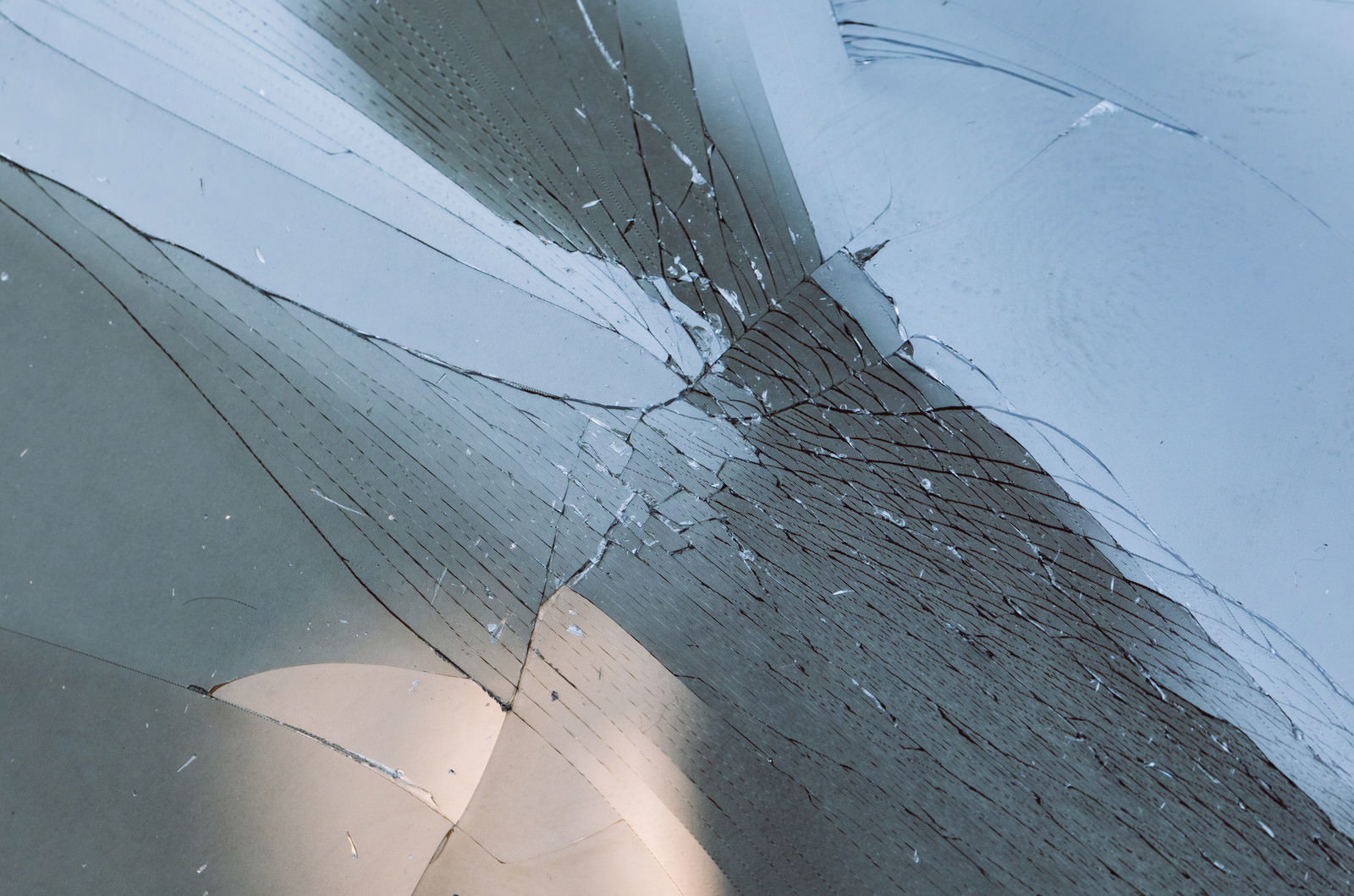 透明なガラス表面に細かなひび割れが放射状に広がっている様子