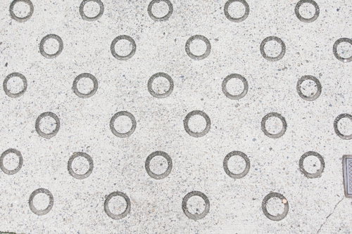 グレーのコンクリート舗装に規則正しく配置された丸いスリップ防止パターン
